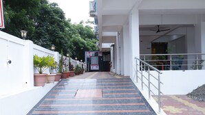 A staircase leading to a building entrance with potted plants along the sides. - Balaji Lodging (Pandharpur)