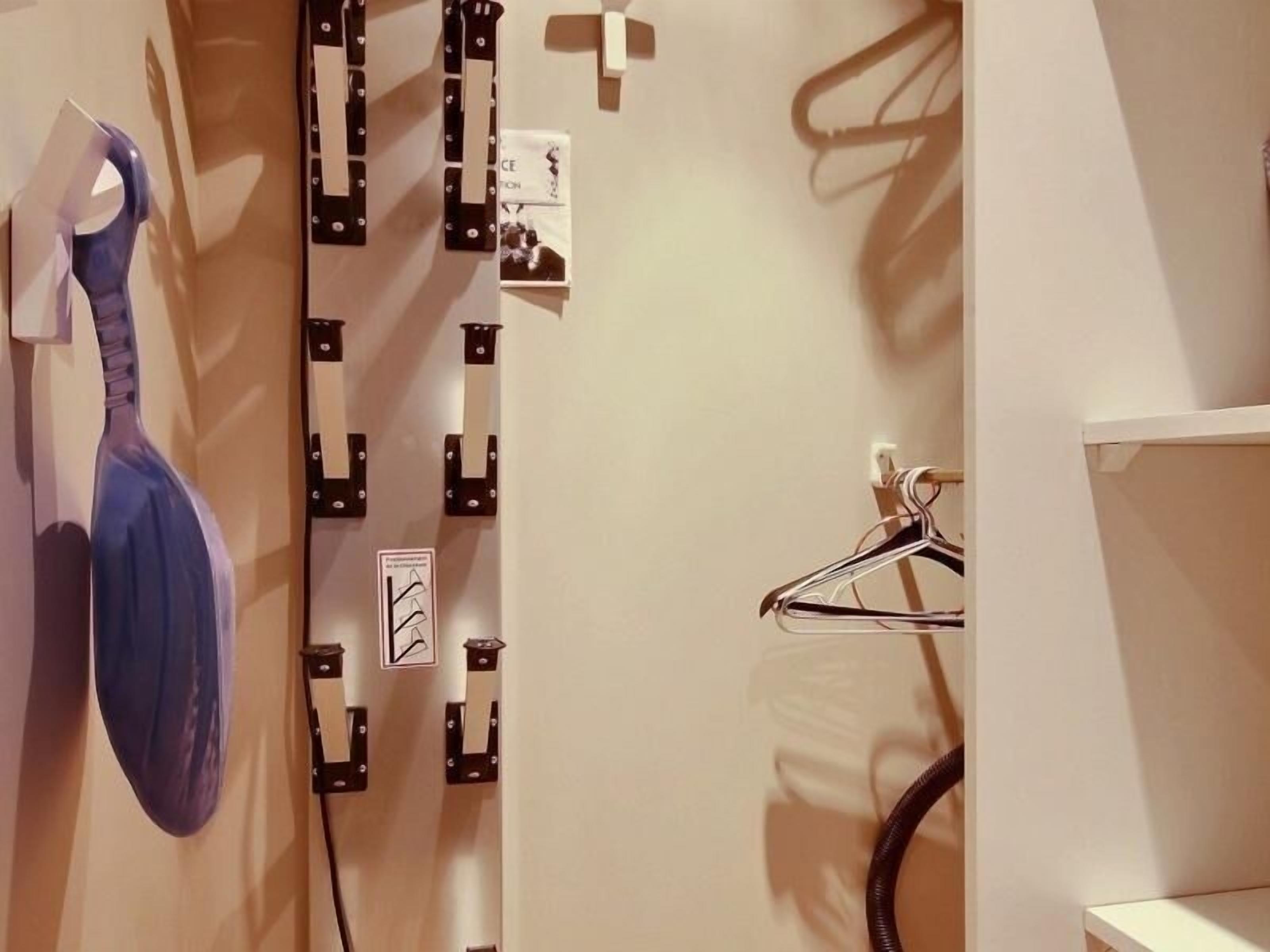 A bathroom with a towel rack, a coat rack, and a shower curtain rod.