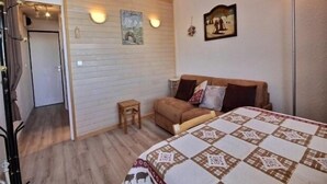 Een slaapkamer met een bed, een klein houten krukje, een bank en een schilderij aan de muur.