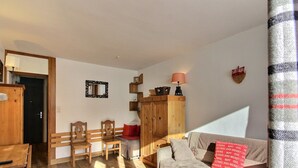 A cozy living room with a sofa, a wooden cabinet, and a dining area with chairs and a table. - Renovated studio 3 pers, south-facing with balcony in La Plagne (La Plagne)