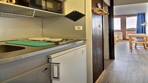 Une cuisine compacte équipée d’un four à micro-ondes, d’un évier et d’une planche à découper verte.