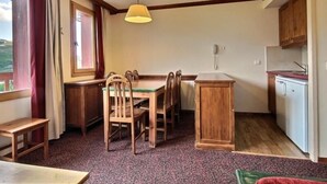 A compact kitchen with a dining area, wooden furniture, and a view through the window.