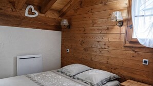 A wooden-paneled room with a bed, bedside lamps, and a window with curtains.