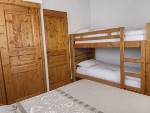 A bunk bed with a wooden headboard and a single bed with a patterned bedspread.