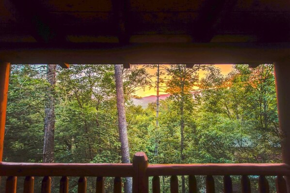 Una ventana con vista a un área boscosa y un edificio a lo lejos.