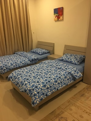Habitació amb dos llits, cadascun amb roba de llit de motius estrellats blaus i blancs.