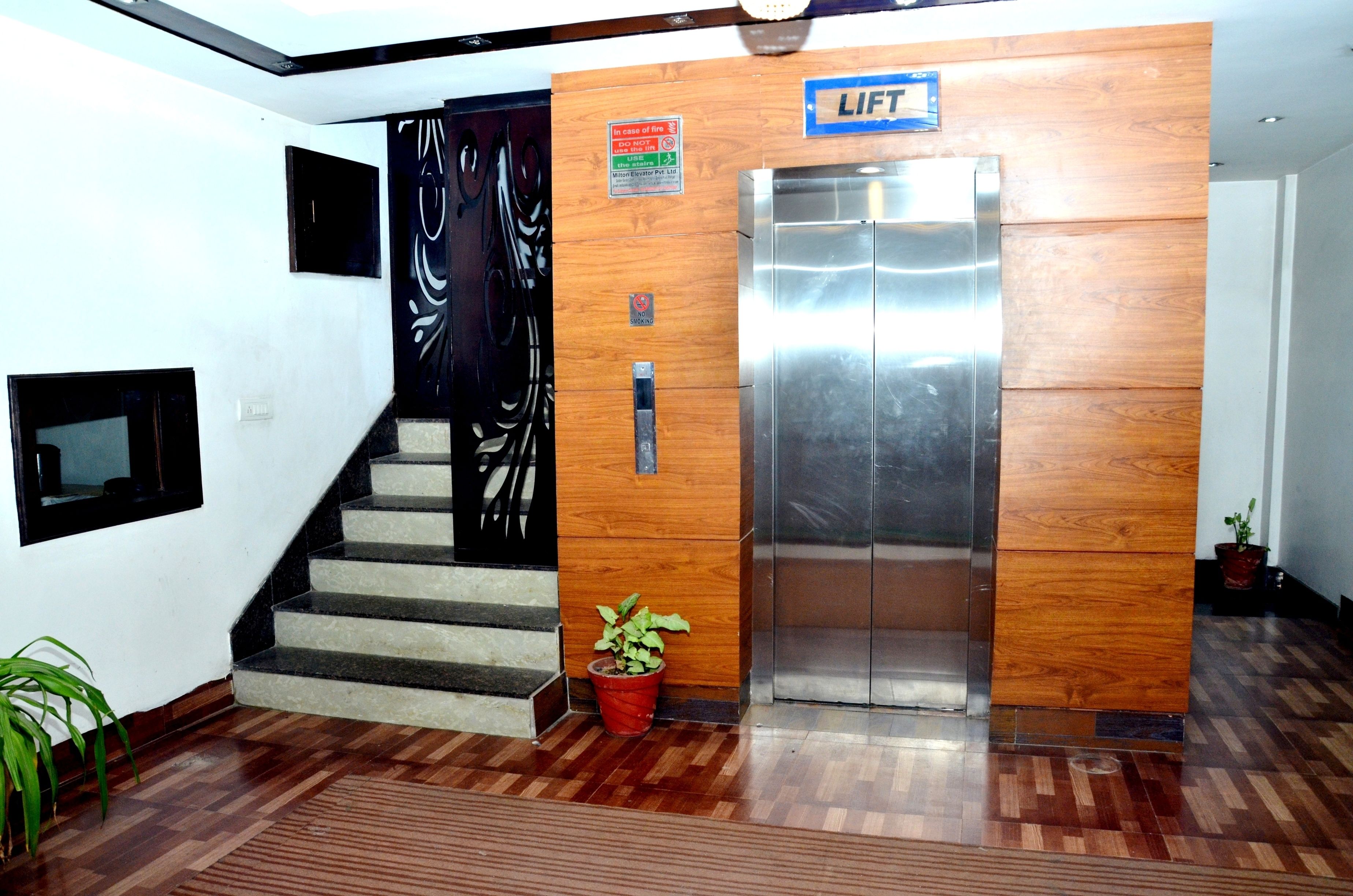 Ein Aufzug mit Holzvertäfelung, eine Treppe mit einem Blumentopf und ein Schild, das den Standort des Aufzugs angibt.