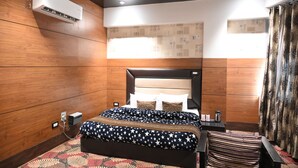 Habitación de hotel con una cama grande, una pared de madera, un equipo de aire acondicionado y una ventana con cortinas.