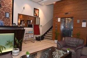 A reception area with a reception desk, a staircase, and an elevator. - Hotel BR Inn (Panipat)
