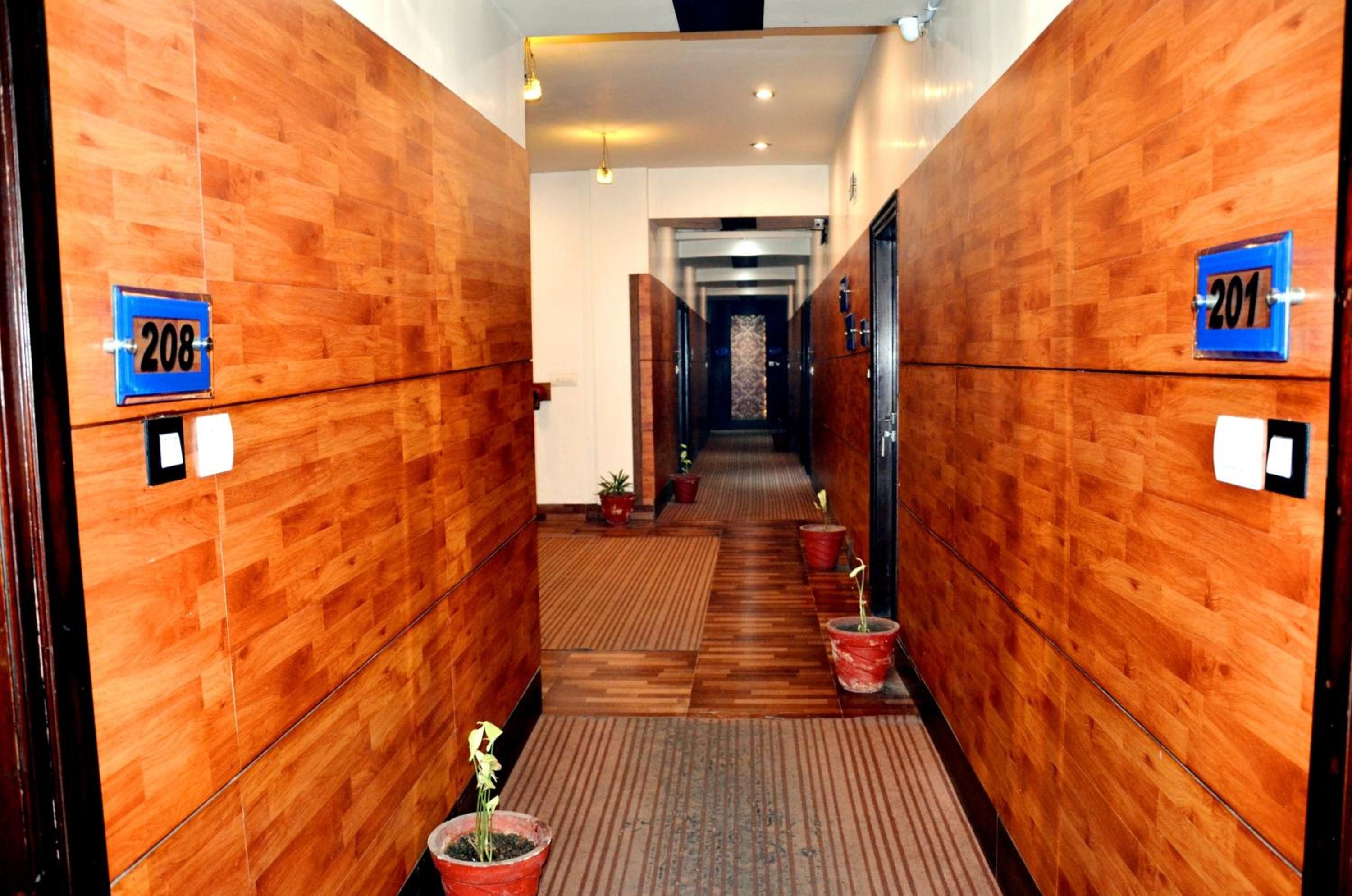 Een hotelgang met houten wanden, genummerde deuren en potplanten.
