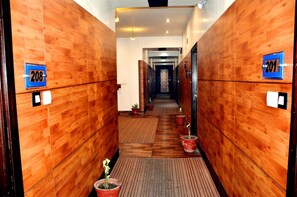 A hotel corridor with wooden walls, numbered doors, and potted plants. - Hotel BR Inn (Panipat)