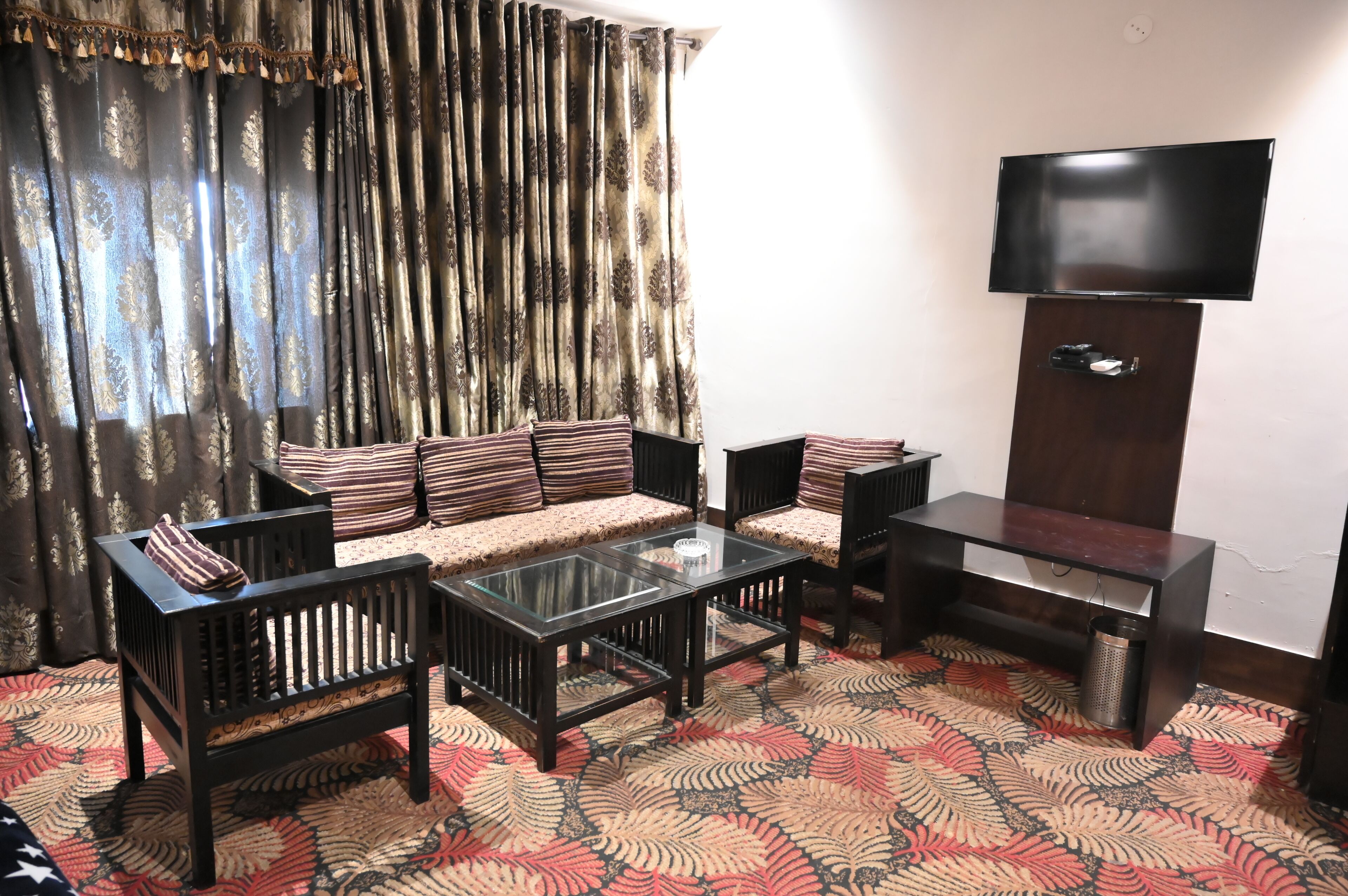 A living room with a sofa, two armchairs, a coffee table, and a TV mounted on the wall.