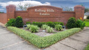 Un mur de briques sur lequel est inscrit le texte « Rolling Hills Estates » et des parterres de fleurs aménagés.