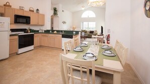 Une cuisine moderne avec des meubles en bois, une table à manger pour quatre personnes et une grande fenêtre.
