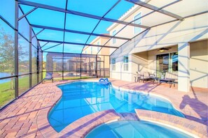 Ein Schwimmbad mit Glasveranda, Gartenmöbeln und Blick auf ein Gebäude im Hintergrund.