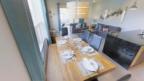 A dining area with a wooden table set for four, a black granite island, and a modern chandelier. - Aco235895 - The Retreat at Champions Gate - 3 Bed 3 Baths Townhome (Clermont)