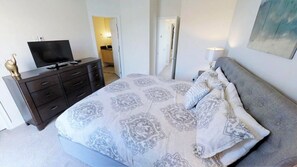 A bedroom with a bed, a dresser, a television, and a lamp. - Aco235895 - The Retreat at Champions Gate - 3 Bed 3 Baths Townhome (Clermont)