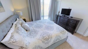 A bedroom with a bed, a dresser, a television, and a window with curtains. - Aco235895 - The Retreat at Champions Gate - 3 Bed 3 Baths Townhome (Clermont)