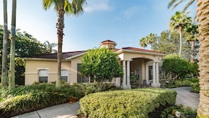 A two-story house with a red-tiled roof, a covered porch, and a well-maintained garden with various plants and a pathway leading to the entrance. - Fv57771 - Emerald Island - 3 Bed 3 Baths Townhome (Kissimmee)