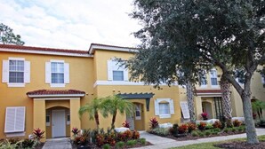 A yellow building with a red-tiled roof, white shutters, and a small front porch. - Fv57771 - Emerald Island - 3 Bed 3 Baths Townhome (Kissimmee)