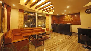 A Durbar Inn reception area with a leather sofa, a reception desk, and a large window. - Durbar Suite (Pokhara)