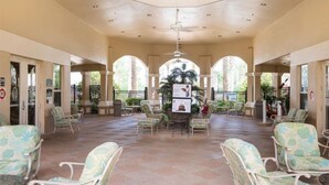 Un espace extérieur abrité, aménagé avec des chaises et des tables, et entouré d’arcades et d’une fontaine centrale.