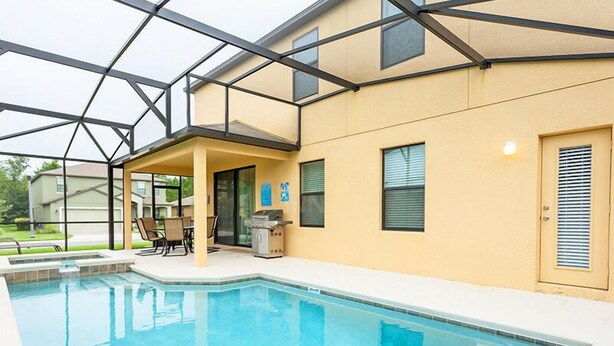 A swimming pool with a covered patio area, a grill, and a door with a window. - Fv49464 - Cypress Pointe - 5 Bed 4.5 Baths Villa (Davenport)