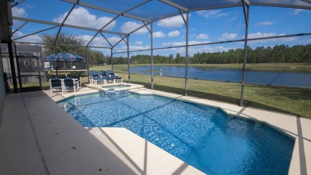 A covered swimming pool with lounge chairs and a view of a lake.