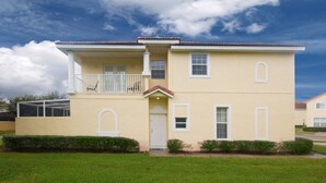 A two-story building with a balcony, a front door, and a small porch. - Ip60382 - Fiesta Key - 4 Bed 3.5 Baths Townhome (Kissimmee)