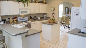 A kitchen with white cabinets, a central island, a stove, and a refrigerator. - Ip60138 - Highlands Reserve - 5 Bed 3 Baths Villa (Davenport)