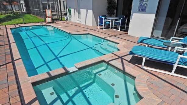 A swimming pool with lounge chairs and a hot tub area.