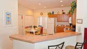 A compact kitchen with a central island, wooden cabinets, and a dining area with chairs.