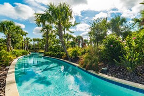 A curved swimming pool surrounded by lush greenery and palm trees. - Aco253282 - Solterra Resort - 4 Bed 3 Baths Townhome (Davenport)