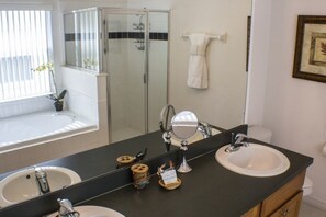 Un baño con dos lavamanos, un espejo grande y una ducha.