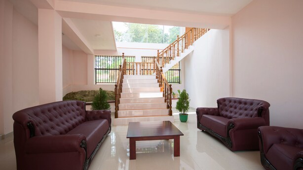 A spacious living area with a staircase, two leather sofas, a wooden coffee table, and a potted plant. - roylanka inn (Udunuwara)