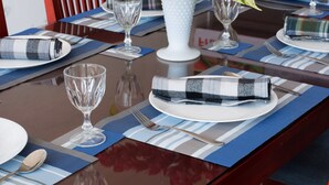 A dining table set with placemats, plates, cutlery, and a vase with flowers. - roylanka inn (Udunuwara)