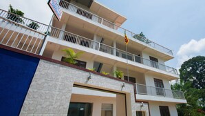 A multi-story building with balconies, a flag, and a signboard. - roylanka inn (Udunuwara)