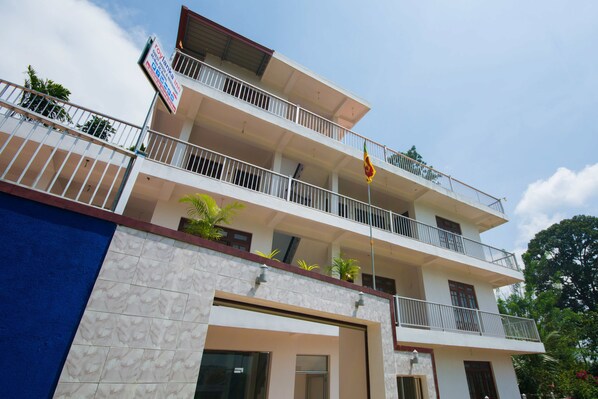 A multi-story building with balconies, a flag, and a signboard. - roylanka inn (Udunuwara)