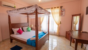 A four-poster bed with a canopy, a bedside table, a mirror, and a wooden cabinet in a room with pink walls and tiled flooring. - roylanka inn (Udunuwara)