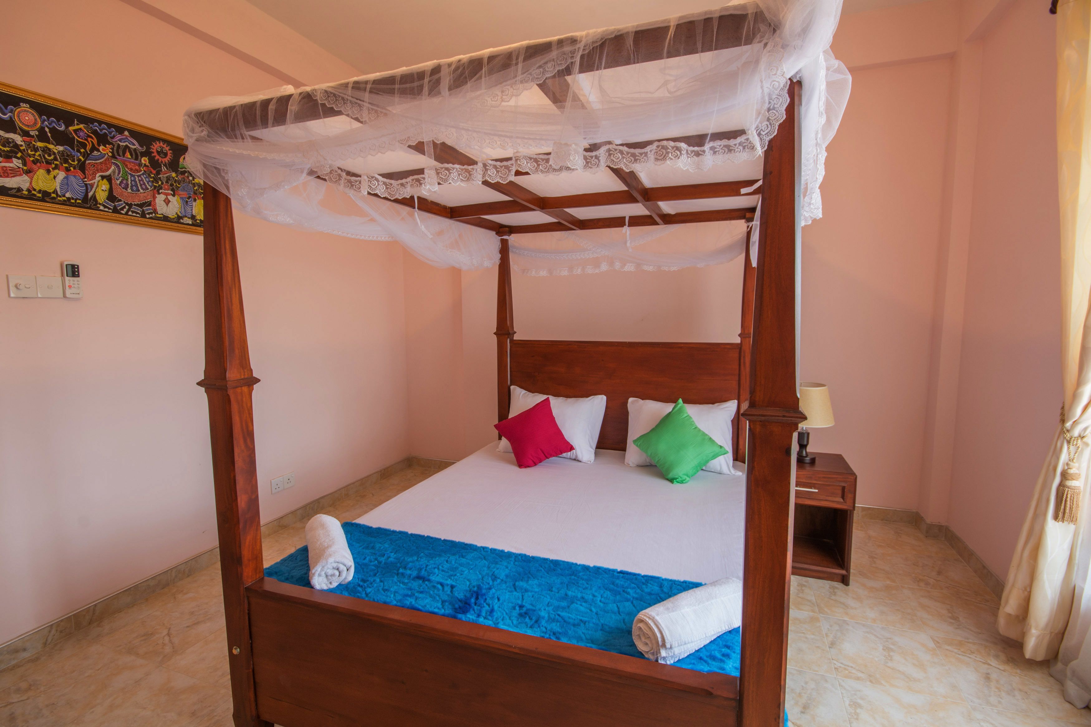 A four-poster bed with a canopy, a blue blanket, and two pillows.