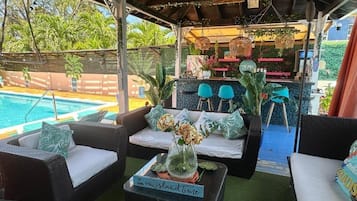 Un espacio al aire libre cubierto con mobiliario de mimbre, una piscina y una zona de bar/lounge.