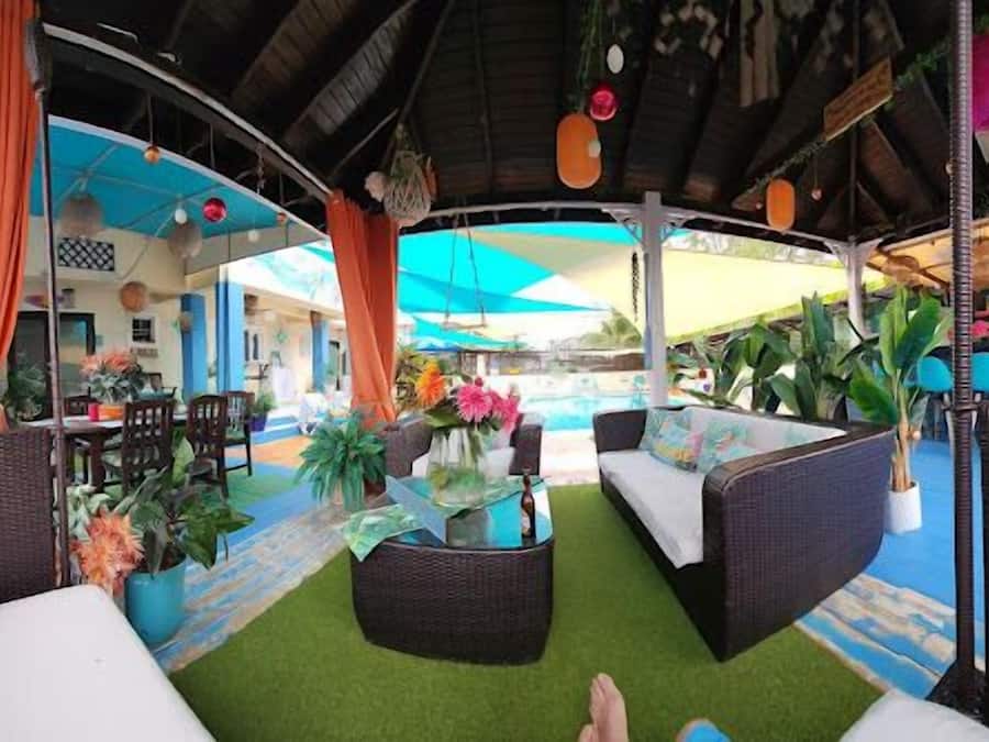 A covered outdoor seating area with wicker furniture, a small table, and potted plants.