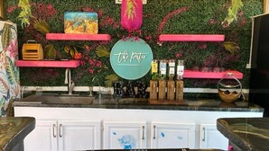 A bar area with a green wall, pink shelves, and a sign that reads "the patio".