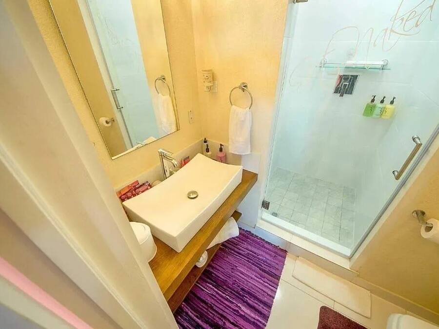 Un baño con lavamanos, espejo, toallero y cabina de ducha de vidrio.