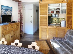 A cozy room with a wooden dining table, a sofa, and a kitchen area with wooden cabinets and a microwave. - 3-room ski-in/ski-out with parking, Wi-Fi included, Val Claret (Tignes)