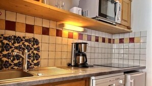 Een keuken met een magnetron, koffiezetapparaat en vaatwasser.