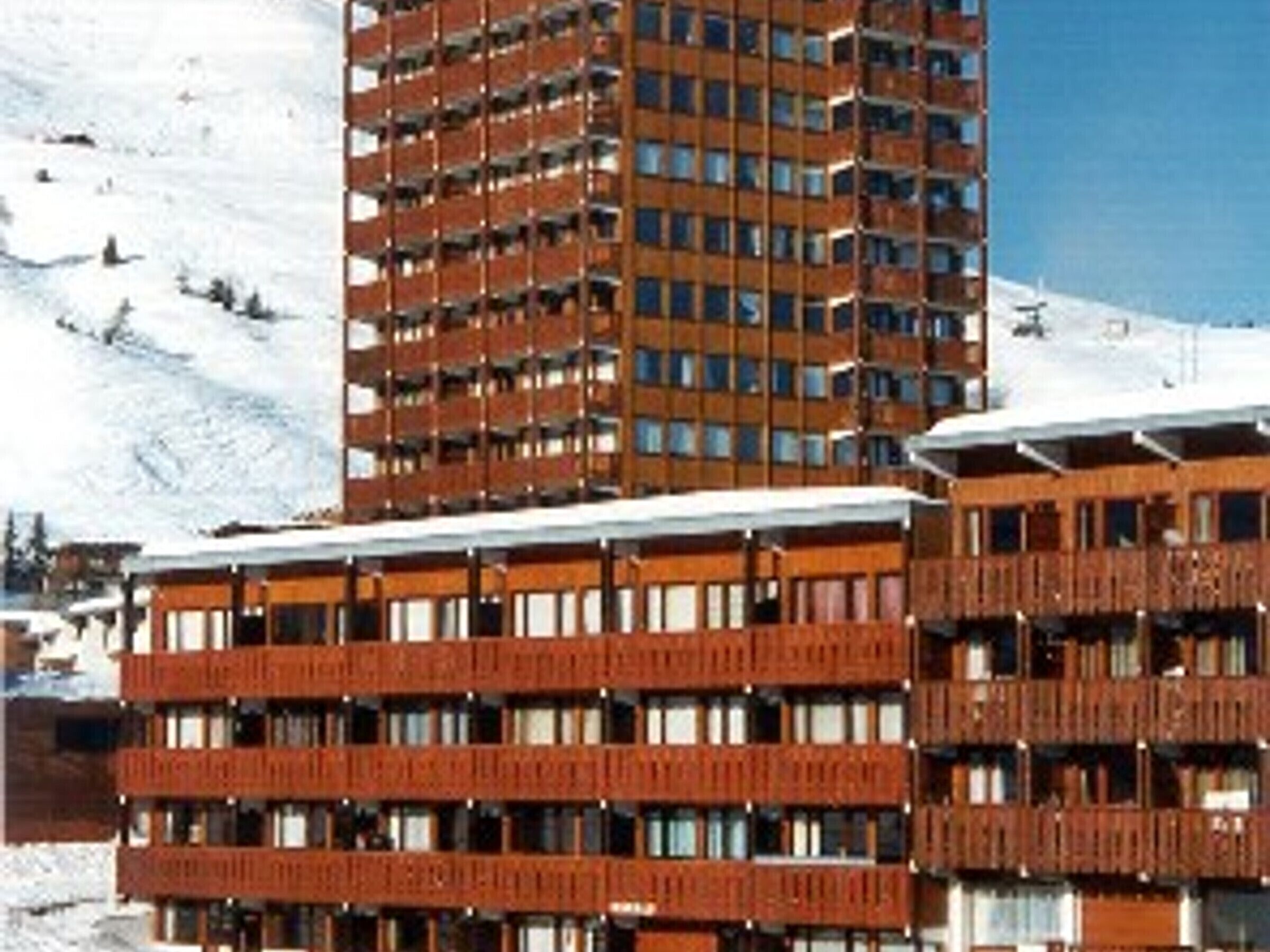 A multi-story hotel with balconies, located in a snowy area.