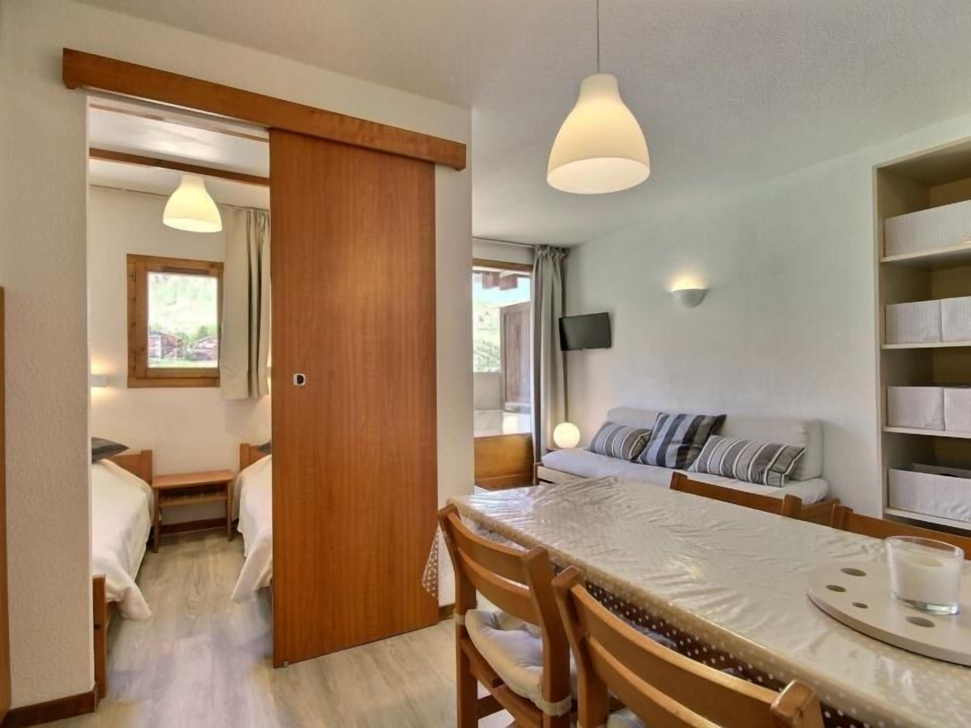 Ein gemütliches Zimmer mit Esstisch, Stühlen, einer Couch und einem Fernseher.