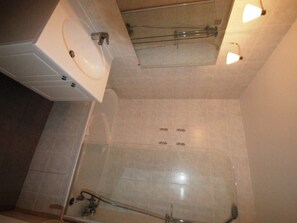 A bathroom with a glass shower enclosure, a sink, and a towel rack.