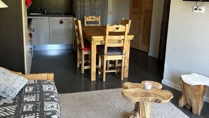 Ein kompakter Wohnbereich mit Essplatz, einer Küchenzeile und einem an der Wand befestigten Fernseher.